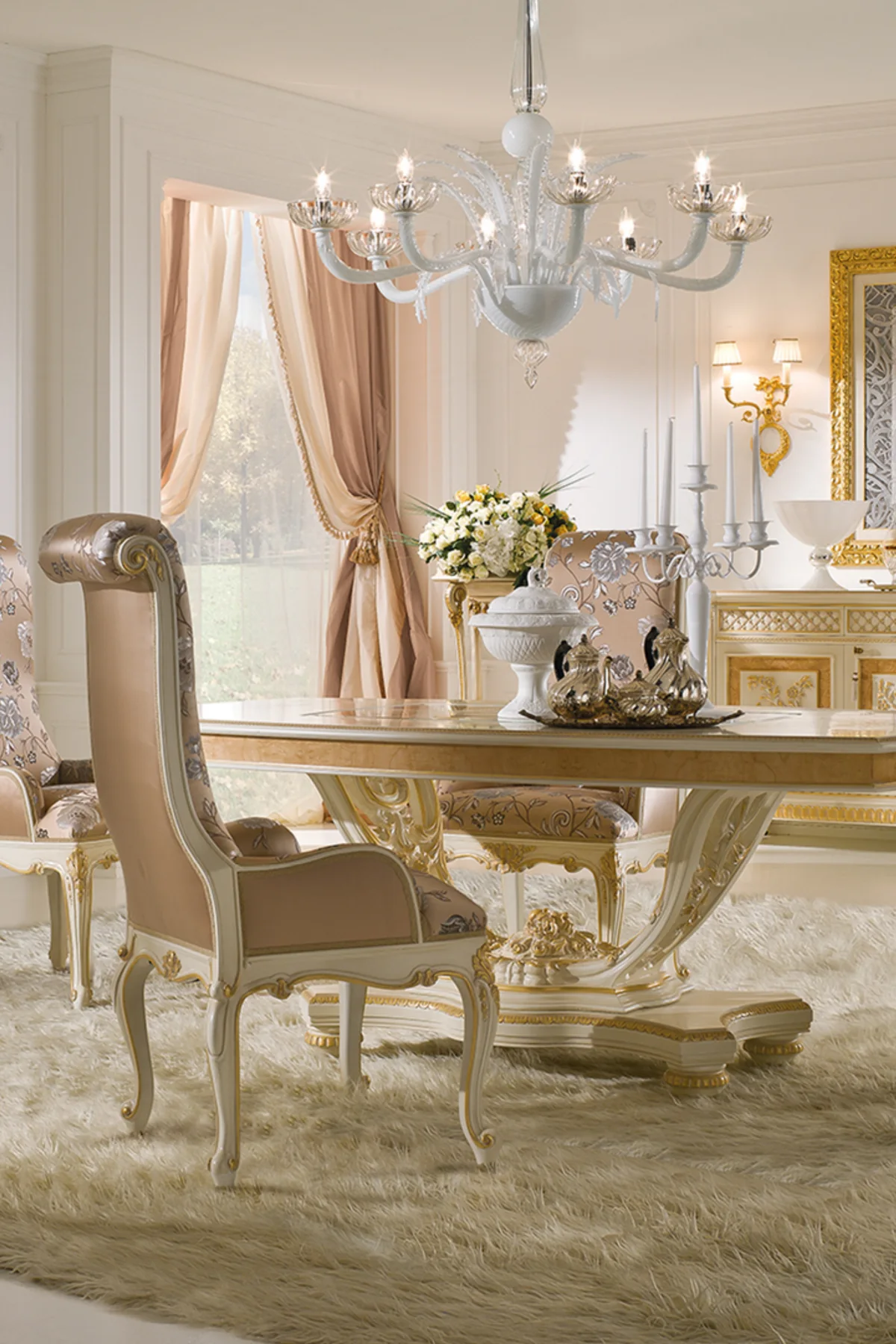 Classic Italian dining room with a carved ivory table, upholstered chairs and a crystal chandelier