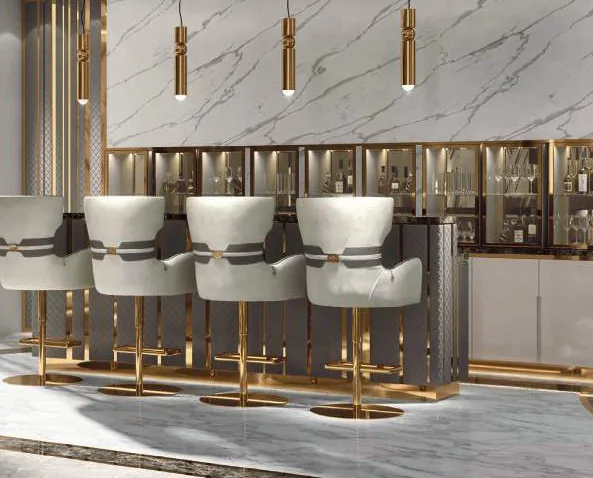 Avant Garde: white leather bar stools with gold bases at a marble bar